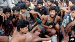 FILE - In this May 20, 2015, file photo, migrants including Myanmar's Rohingya Muslims sit on the deck of their boat as they wait to be rescued by Acehnese fishermen on the sea off East Aceh, Indonesia. Myanmar called sad and regrettable a move by the United States to place the country on a list of the world's worst human trafficking offenders, while rights groups welcome it as long overdue.