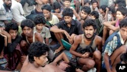 FILE - In this May 20, 2015, file photo, migrants including Myanmar's Rohingya Muslims sit on the deck of their boat as they wait to be rescued by Acehnese fishermen on the sea off East Aceh, Indonesia. Myanmar called sad and regrettable a move by the Uni