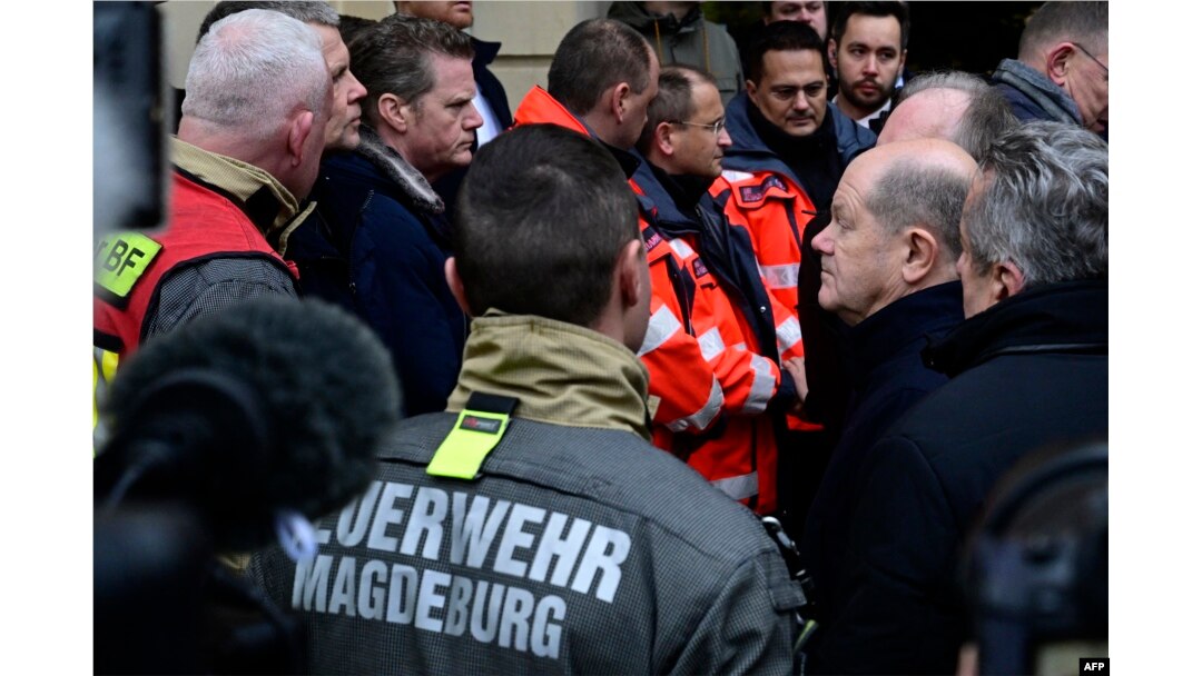 German Chancellor Olaf Scholz, right, talks to rescuers during a visit to the site of a car-ramming attack on a Christmas market in Magdeburg, Germany, on Dec. 21, 2024.