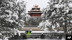 En esta imagen, distribuida por la agencia noticiosa estatal de China, Xinhua, un trabajador retira la nieve cerca de una Torre de la Ciudad Prohibida tras una intensa nevada, en Beijing, el 21 de febrero de 2024.