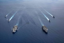 FILE - In this photo provided by U.S. Navy, the USS Ronald Reagan (CVN 76) and USS Nimitz (CVN 68) Carrier Strike Groups steam in formation, in the South China Sea, July 6, 2020.