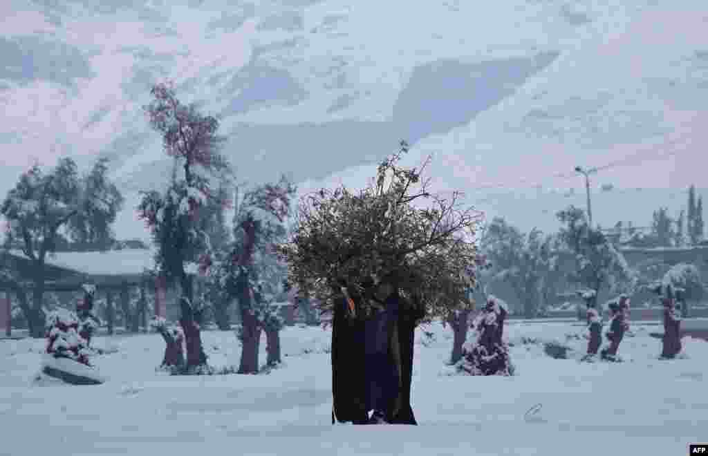 A Syrian man carries wood for a fire in the rebel-held city of Douma, Jan. 11, 2015.