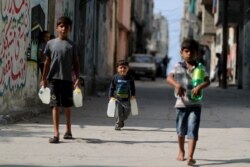 Palestinian boys carry bottles of water as they walk in Al-Shati refugee camp in Gaza City Oct. 23, 2019.