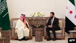 د شام عربي خبري ایجنسۍ سانا دا عکس د 2025م کال د جنورۍ په 24مه خپور کړی چې پکې د شام نوی مشر احمد الشرع په دمشق کې د سعودي عرب د بهرنیو چارو له وزیر فیصل بن فرحان سره ملاقات کوي.