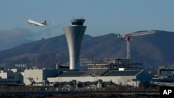 FILE - A plane takes off behind the air traffic control tower at San Francisco International Airport, in San Francisco, California, Nov. 24, 2020.