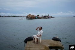 Evelio Lopez tries to get a cell phone connection on a dock on Gardi Sugdub island, part of the San Blas archipelago off Panama's Caribbean coast, on May 25, 2024.