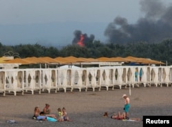 Ілюстративне фото. Люди на пляжі на тлі диму й полум'я після вибухів на російській військовій авіабазі в Новофедорівці, Крим, 9 серпня 2022 р. REUTERS