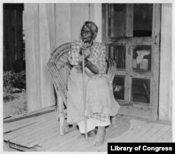 FILE - Lucinda Davis, guessed to be 89 years-old at the time, sits on the front porch of her home in Tulsa, Oklahoma, Aug. 16, 1937. She was the former slave of a full-blooded Muscogee Creek farmer named Tuskaya-hiniha. (Library of Congress)