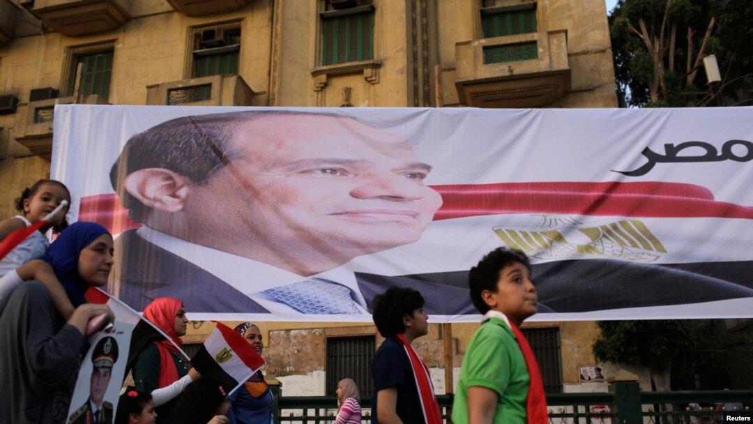 Egyptians walk by a poster for former Egyptian army chief Abdel Fattah al-Sisi in Tahrir square as they arrive to celebrate his victory in the presidential vote in Cairo, June 3, 2014.