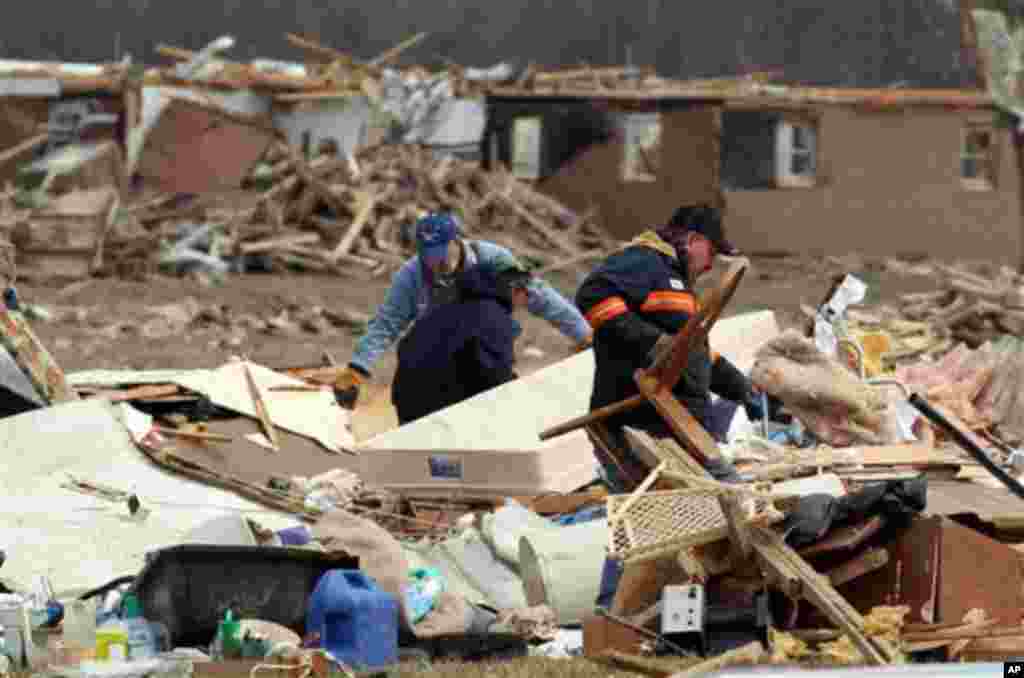 Dale Kirk, right, picks up a chair from the debris of the home of Brenda and Ted Tolbert of Holton, Ind. on Sunday, March 4, 2012.