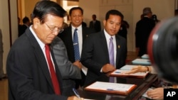 Cambodia National Rescue Party's Vice President Kem Sokha, left, registers before a meeting at at National Assembly, in Phnom Penh, Cambodia, Friday, Aug. 8, 2014. Lawmakers from opposition Cambodia National Rescue Party on Friday appeared for the first time at the meeting of National Assembly, ending their ten months of boycott of parliament over claims that the results of the July 2013 general election were rigged. (AP Photo/Heng Sinith) 