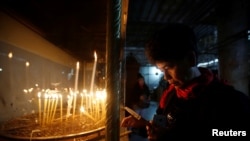 Un visiteur allume une bougie à l'intérieur de l'Église de la Nativité pour Noël à Bethléem, le 25 décembre 2016. 