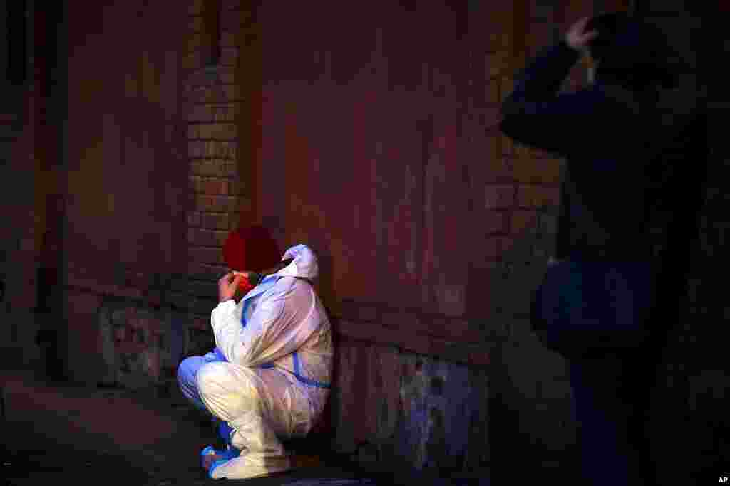 An emergency medical worker rests against a wall outside the Matei Bals hospital in Bucharest, Romania, where officials say an early-morning fire killed four people.
