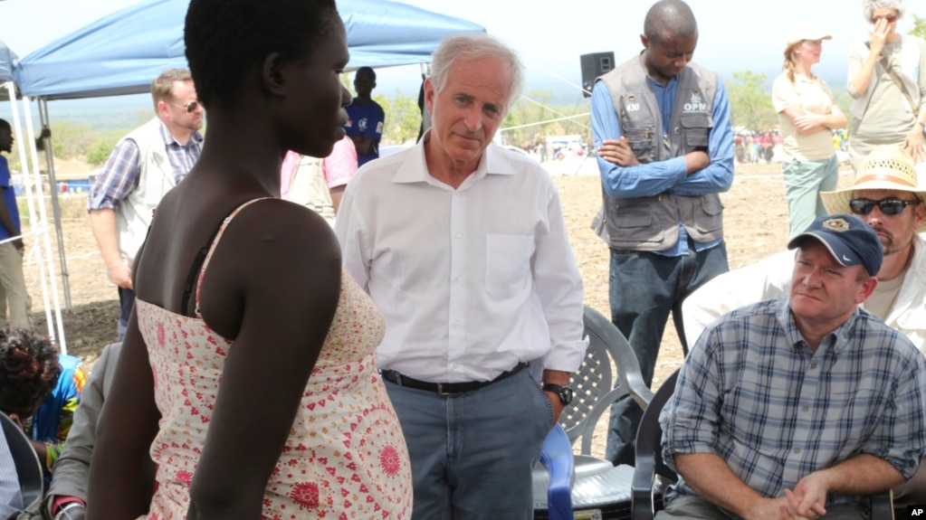 U.S Senators Bob Corker, center, and Chris Coons, right, speak with a South Sudanese refugee during a group discussion at the Bidi Bidi refugee settlement in northern Uganda, April 14, 2017.