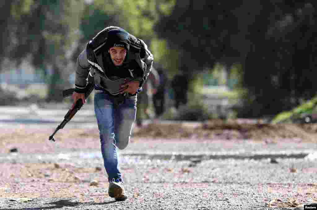 A Free Syrian Army fighter runs for cover at a suburb of Damascus, January 17, 2013.
