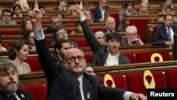 FILE - Lluis Corominas of Junts per Catalunya and Sergi Sabria of Republican Left of Catalonia (ERC) vote during a debate in the regional parliament in Barcelona, Spain, May 4, 2018.