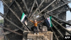 A boy waves the opposition Syrian flag as he stands in one of the water wheels, or norias, in Hama, after anti-government fighters captured the central city.