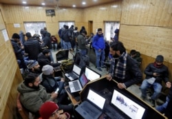 FILE - Journalists use the internet as they work inside a government-run media center in Srinagar, Jan. 10, 2020.