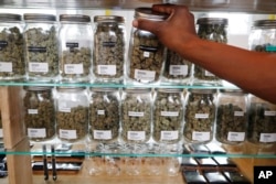 FILE - A clerk reaches for a container of marijuana buds for a customer at Utopia Gardens, a medical marijuana dispensary, in Detroit, Oct. 2, 2018.