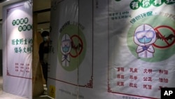 FILE - A worker wearing a mask peeps out behind construction barrier with a notice depicting a bat and advocating for people not to eat wild animals at the airport in Kunming in southern China's Yunnan province on Thursday, Dec. 3, 2020. (AP Photo/Ng Han Guan)