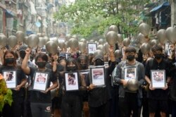 FILE - Anti-coup protesters holding pictures of those who died during a protest against the military offer prayers for them, in Yangon, Myanmar, Monday, April 5, 2021.