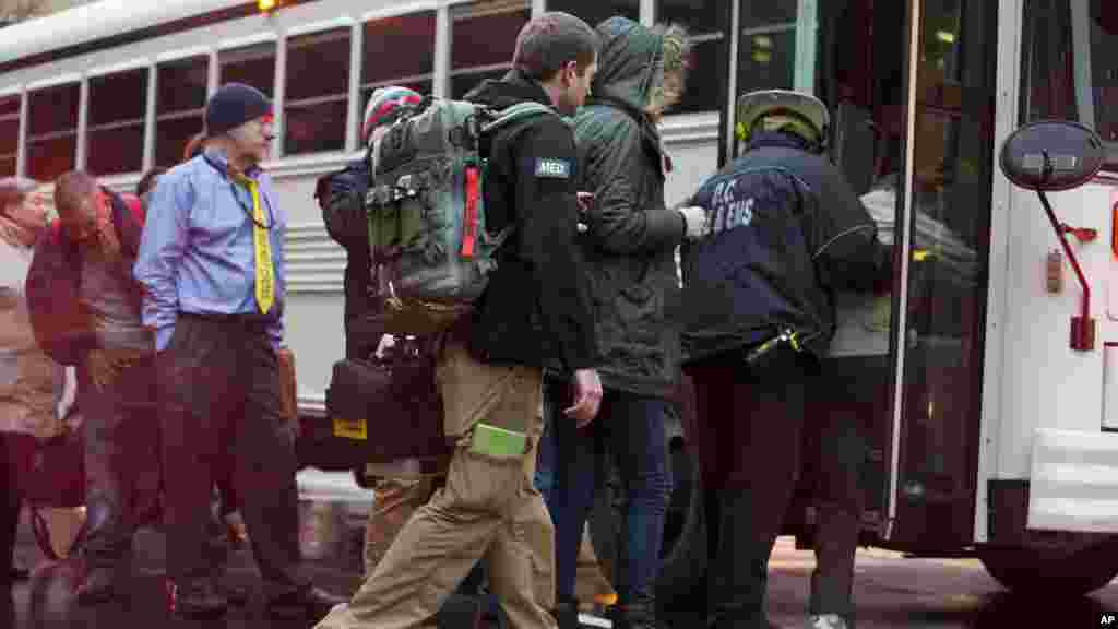 Un personnel medical du FBI, centre, aide les personnes évacuées d&#39;un tunnel de métro enfumé à embarquer dans un bus à Washington, lundi 12 janvier, 2015.