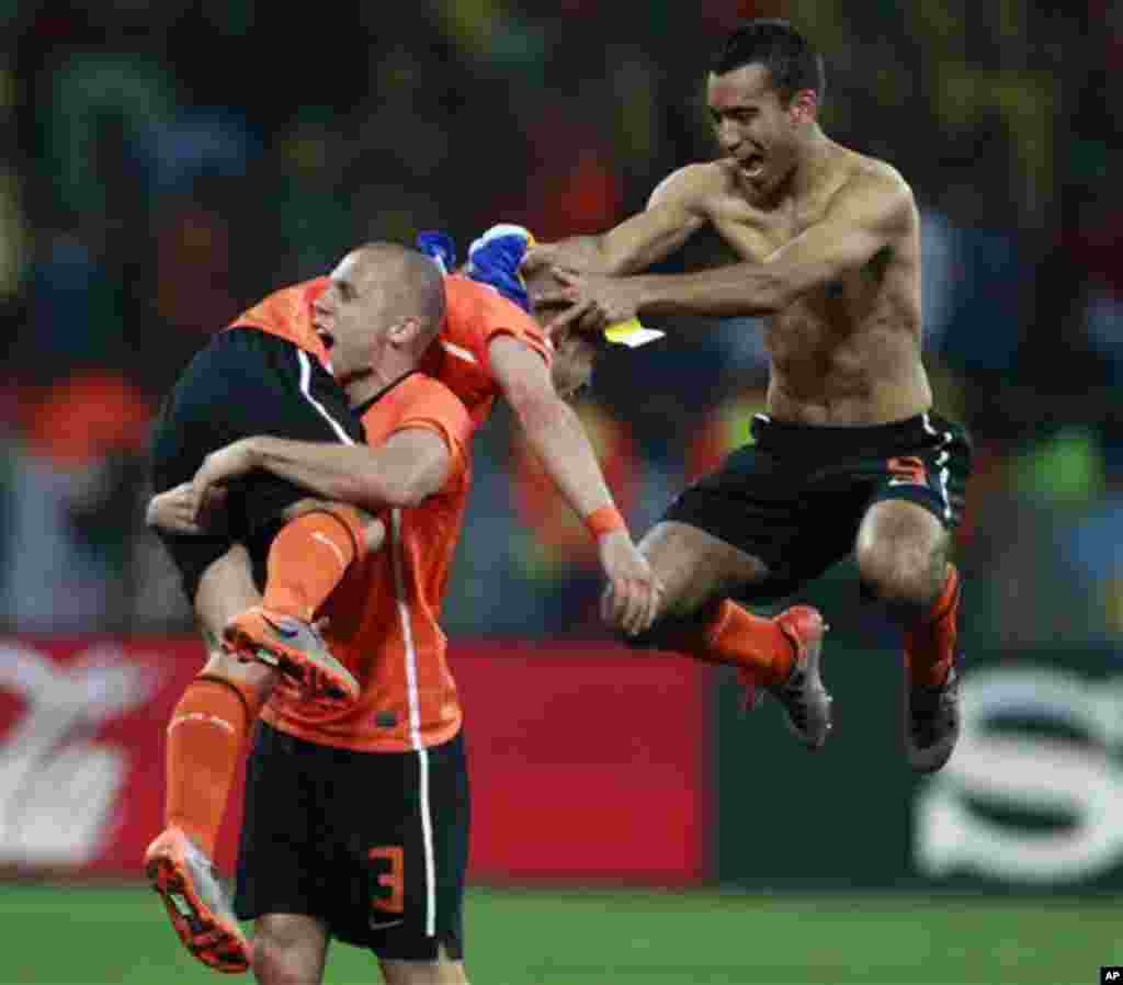 Netherlands' John Heitinga, bottom, carries teammate Wesley Sneijder, top, as teammate Giovanni van Bronckhorst celebrates near them at the end of the World Cup quarterfinal soccer match between the Netherlands and Brazil at Nelson Mandela Bay Stadium in