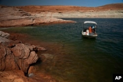 A Utah State University research team works at Lake Powell on June 7, 2022, in Page, Arizona. (AP Photo/Brittany Peterson, File)