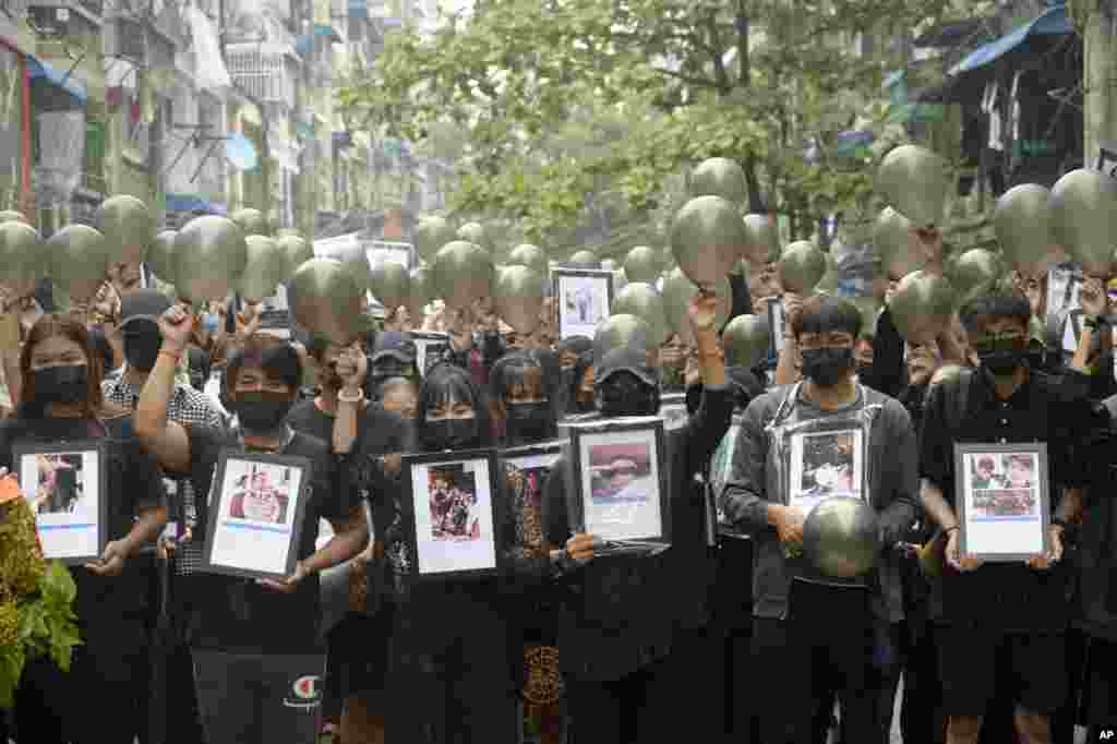 Anti-coup protesters holding pictures of those who died during a protest against the military offer them prayersin Yangon, Myanmar.