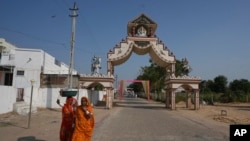 Warga berjalan melewati gapura penanda desa Dingucha di Gandhinagar, India, pada 12 November 2024. (Foto: AP/Ajit Solanki)