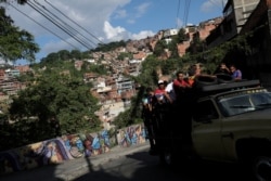 People riding in a truck drive pass by a mural in Petare slum, in Caracas, Venezuela, Aug. 7, 2019.