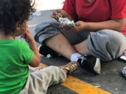 A Honduran migrant and her 18-month-old daughter wait to decide their next steps after being returned to Mexico under the Migration Protection Protocols (MPP) earlier in the day. (V. Macchi/VOA)