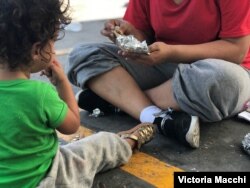 A Honduran migrant and her 18-month-old daughter wait to decide their next steps after being returned to Mexico under the Migration Protection Protocols (MPP) earlier in the day. (V. Macchi/VOA)