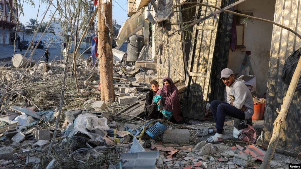 Palestinians sit amid rubble at the site of an Israeli strike on a house, amid the Israel-Hamas conflict, in Nuseirat in the central Gaza Strip, Dec. 1, 2024. 