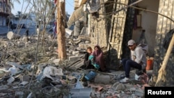 Palestinians sit amid rubble at the site of an Israeli strike on a house, amid the Israel-Hamas conflict, in Nuseirat in the central Gaza Strip, Dec. 1, 2024. 