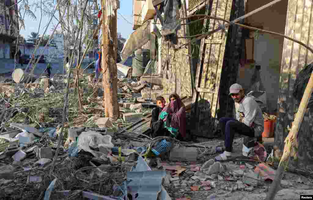 Palestinians sit amid rubble at the site of an Israeli strike on a house in Nuseirat in the central Gaza Strip.