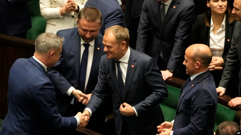 Newly elected Poland's Prime Minister Donald Tusk, center, is congratulated by lawmakers after his government passed a confidence vote at the parliament in Warsaw, Poland, Dec. 12, 2023.