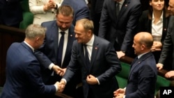Newly elected Poland's Prime Minister Donald Tusk, center, is congratulated by lawmakers after his government passed a confidence vote at the parliament in Warsaw, Poland, Dec. 12, 2023.