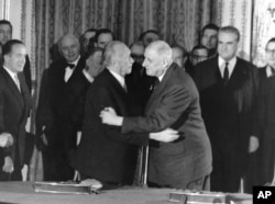FILE - German Chancellor Konrad Adenauer, center left, hugs France President Charles de Gaulle after signing the Elysee friendship treaty in the Elysee palace in Paris, Jan. 22, 1963. The leaders of France and Germany are poised to sign the Aachen accord Jan. 22, 2019, renewing their friendship and pledging greater cooperation.