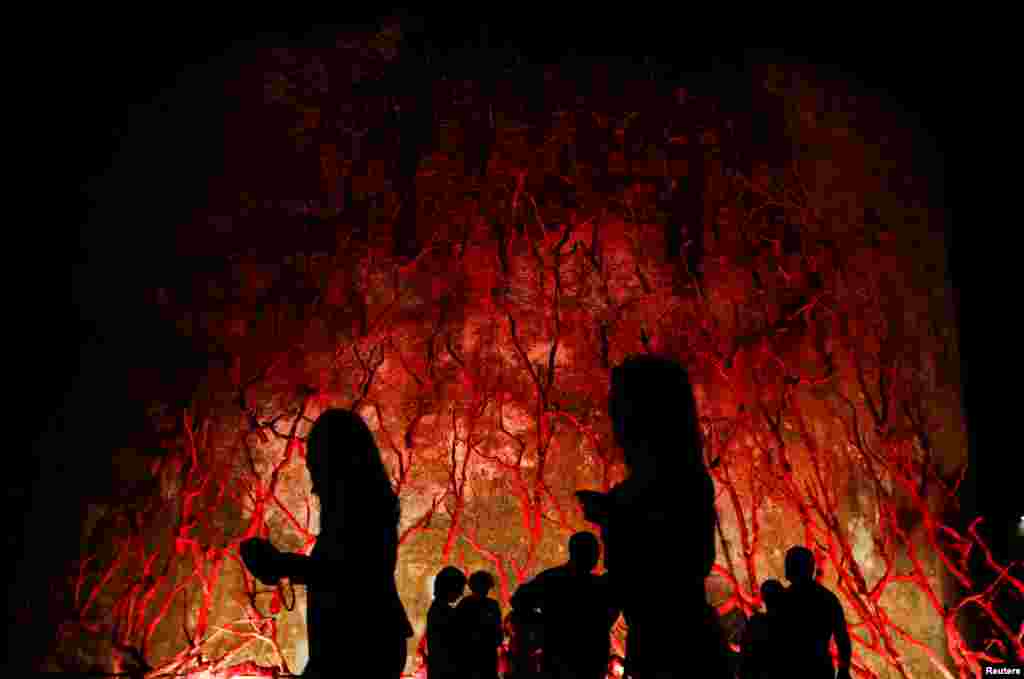 People walk in front of an art installation called &quot;L&#39;albero di corallo&quot; (Coral tree), in Alghero, Italy, Sept. 25, 2021.