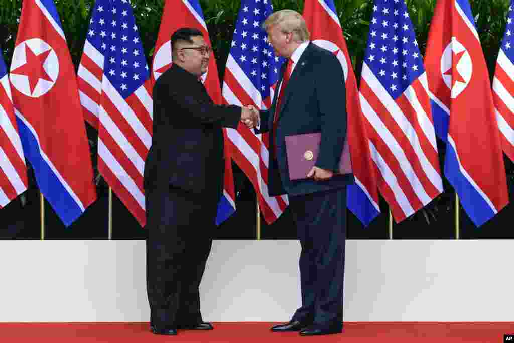 Shugaban Amurka Donald Trump da shugaban Koriya Ta Arewa Kim Jong Un suna shan hannu bayan sa hannu a yarjejeniya a taron kolin da suka gudanar a otel din Capella Hotel dake tsibirin Sentosa, Singapore, Juni 12, 2018.