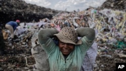 FILE—In this photo taken December 5, 2018, a woman scavenges recyclable materials at the dump in the Dandora slum of Nairobi, Kenya.