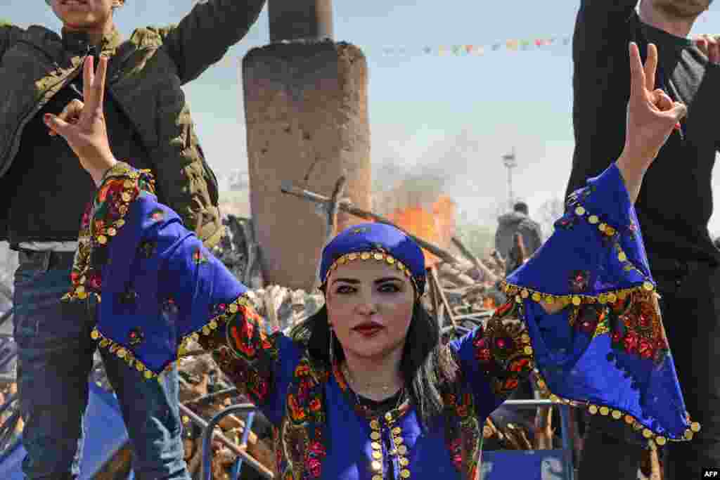A young woman flashes the victory sign in front of a bonfire as Turkish Kurds gather during Newroz celebrations for the new year in Diyarbakir, Turkey.