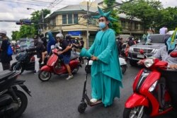 FILE - A pro-democracy protester dressed as the Statue of Liberty rides an electric scooter during an anti-government demonstration marking the anniversary of the 1932 Siamese Revolution, in Bangkok, Thailand, June 24, 2021.
