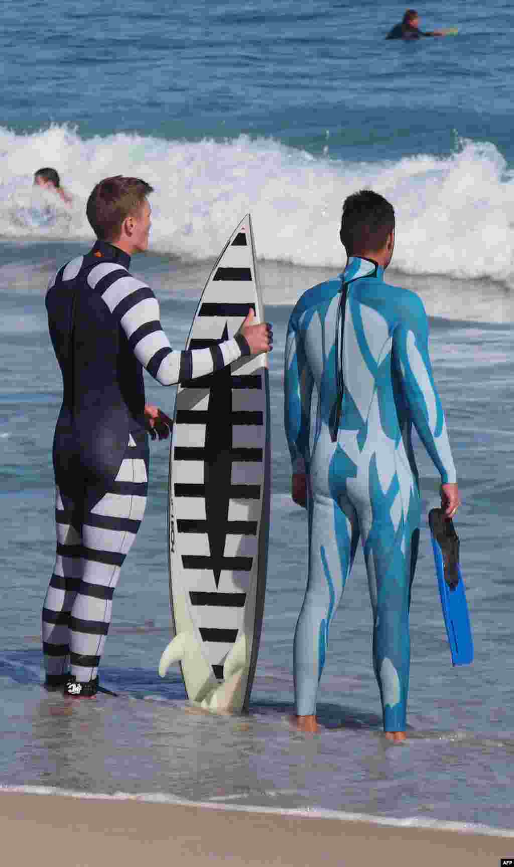 A surfer (L) and a diver (R) wearing wetsuits displaying the two styles of Shark Attack Mitigation Systems (SAMS) shark deterrent technology, with the surfer holding a surfboard also showing the new design. The new technology was designed by SAMS in collaboration with the Oceans Institute at the University of Western Australia, with the two design variations either presenting the wearer as potentially dangerous and unpalatable to a shark, or making it very difficult for the shark to see the wearer in the water. (Shark Attack Mitigation Systems handout photo)