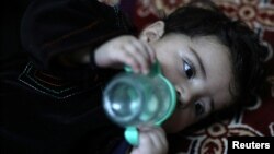 Baby Sohail Ahmadi drinks milk from a bottle inside the house of Hamid Safi, a taxi driver who found Sohail in the airport, in Kabul, Afghanistan, Jan. 7, 2022.