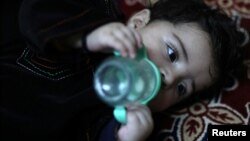 Baby Sohail Ahmadi drinks milk from a bottle inside the house of Hamid Safi, a taxi driver who found Sohail in the airport, in Kabul, Afghanistan, Jan. 7, 2022.