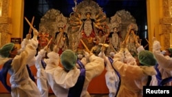 Hindu devotees wearing personal protective equipment perform Dandiya, a traditional dance, in front of an idol of Hindu goddess Durga on the first day of Durga Puja festival in Kolkata, India, Oct. 22, 2020.