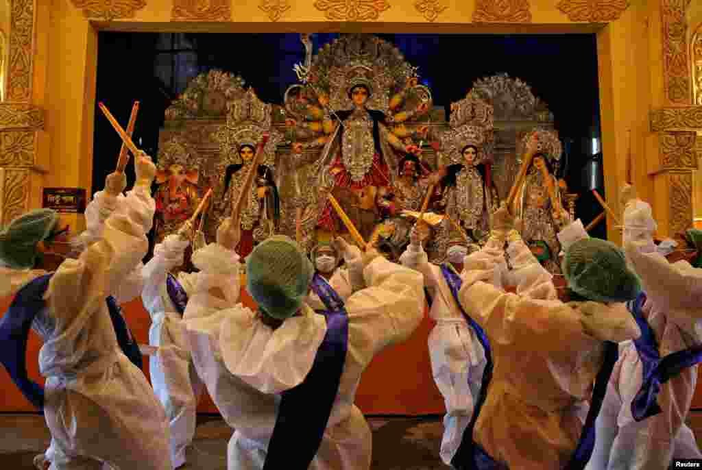 Devotos hindus usando equipamento de protecção individual realizam Dandiya, uma dança tradicional, em frente a um ídolo da deusa hindu Durga no primeiro dia do festival Durga Puja em Calcutá, Índia, em 22 de Outubro de 2020. &nbsp;