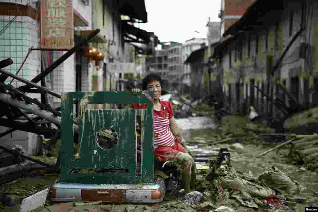 یک زن نشسته در میان ویرانه های که طوفان بحری در ولایت فوجیان چین به میان آورده است.
